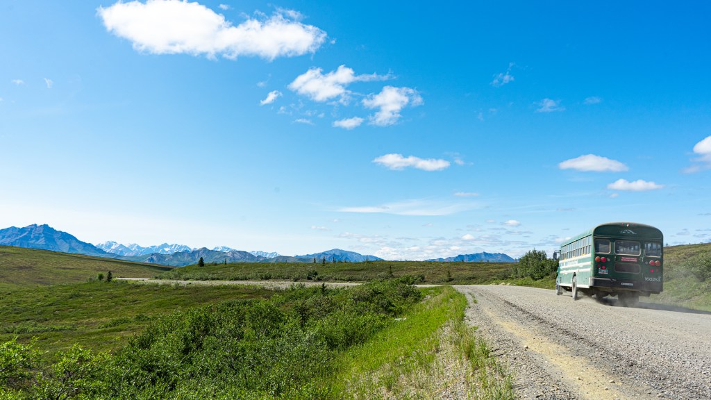 A bus driving down a stone road in Denali National Park, Alaska