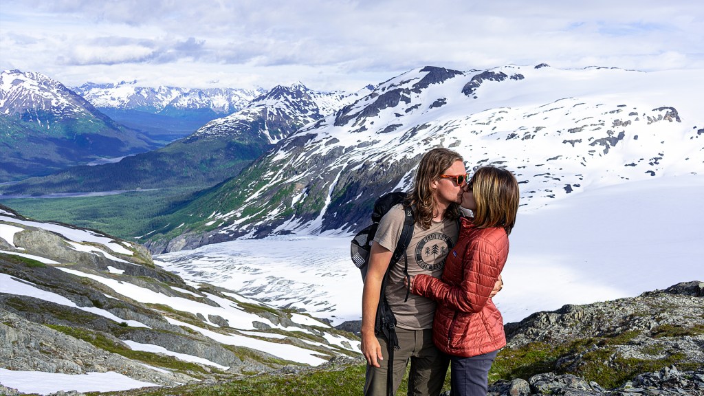 A young man and woman kissing in front of a glacier in Seward, Alaska.