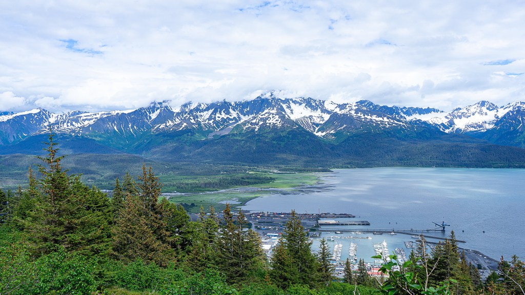 An aerial view taken of a bay with snowy mountain peaks in the background in Seward, Alaska.