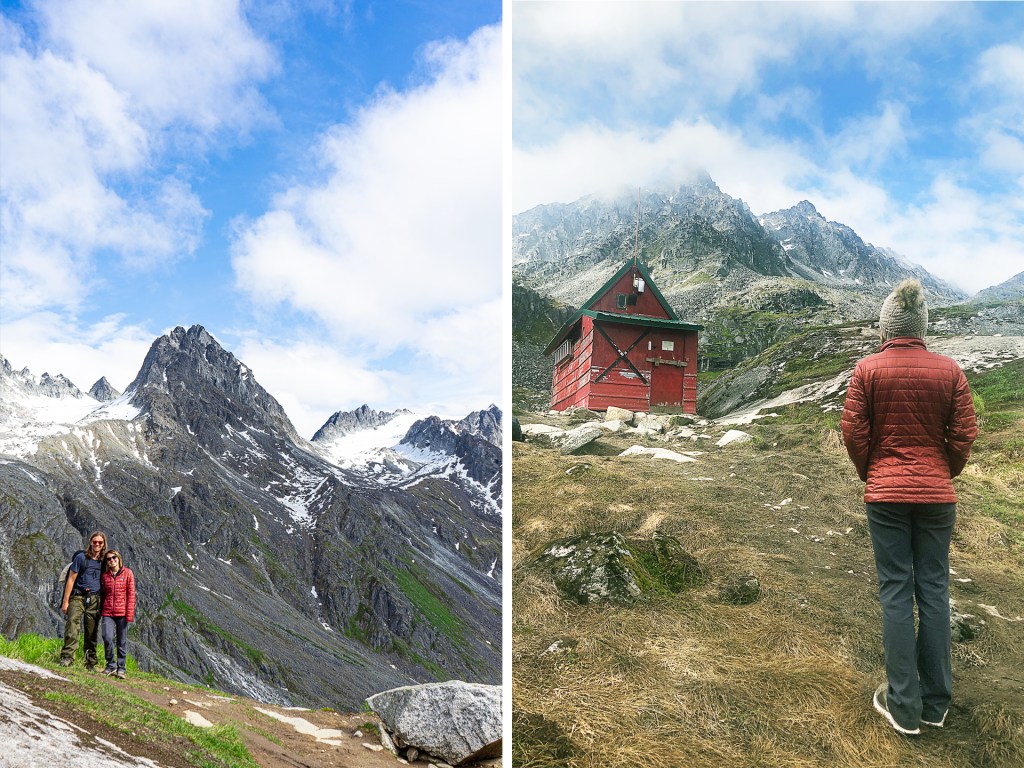 A young man and woman at the peak of a hiking trail, with a red hut, in Alaska.