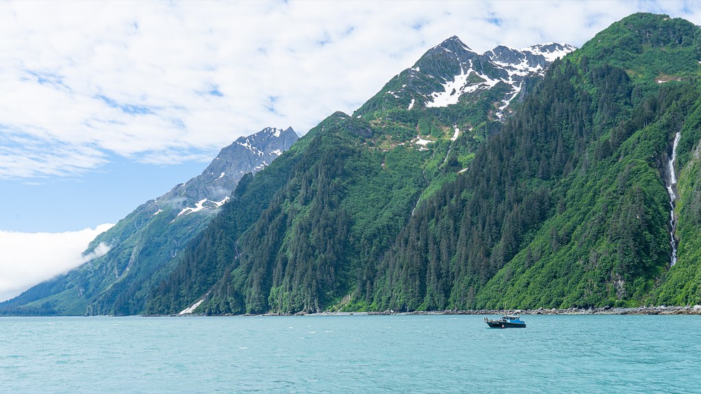 A bright green mountain range with snowy peaks in Valdez, Alaska.