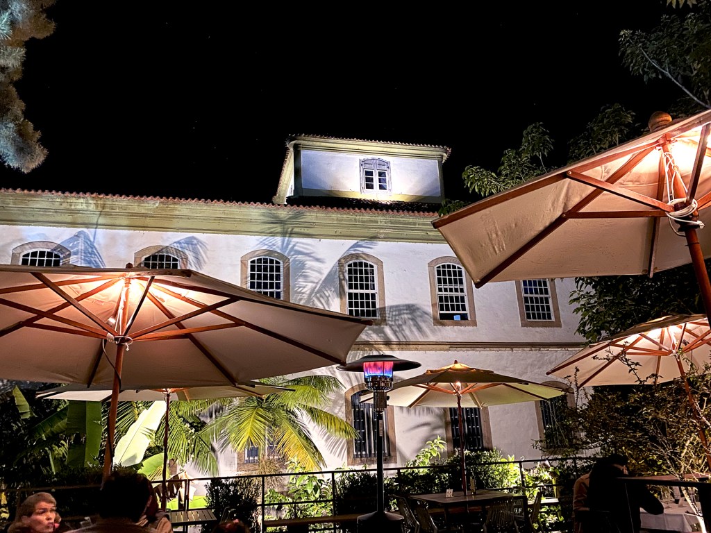 Tables at a restaurant with umbrellas at night time.