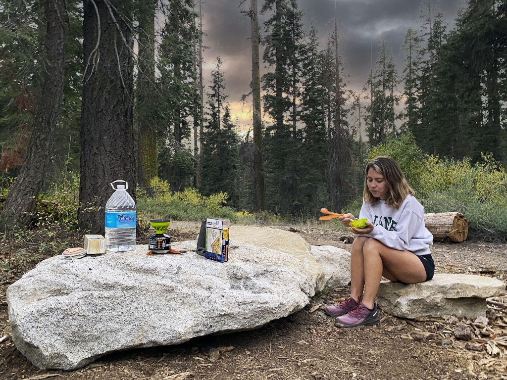 A woman eating food in Sequoia National Park while car camping