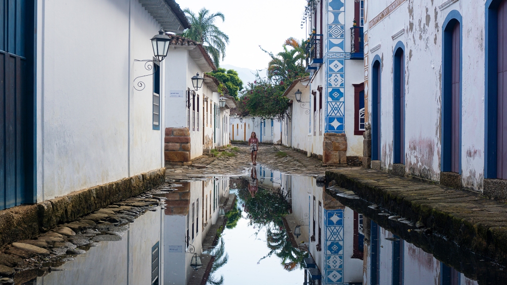 A flooded street in the city of Paraty, Rio de Janeiro, Brazil lined with white 17th century buildings with colorful trim, and cobblestone streets.