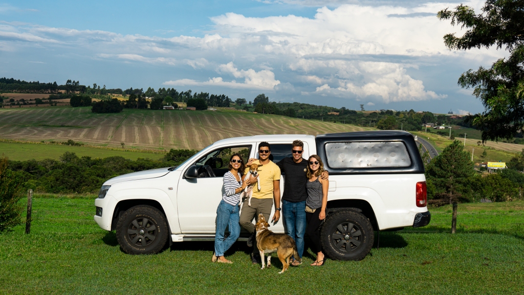 Four friends and two dogs standing in front of a white Volkswagon truck in Brazil.
