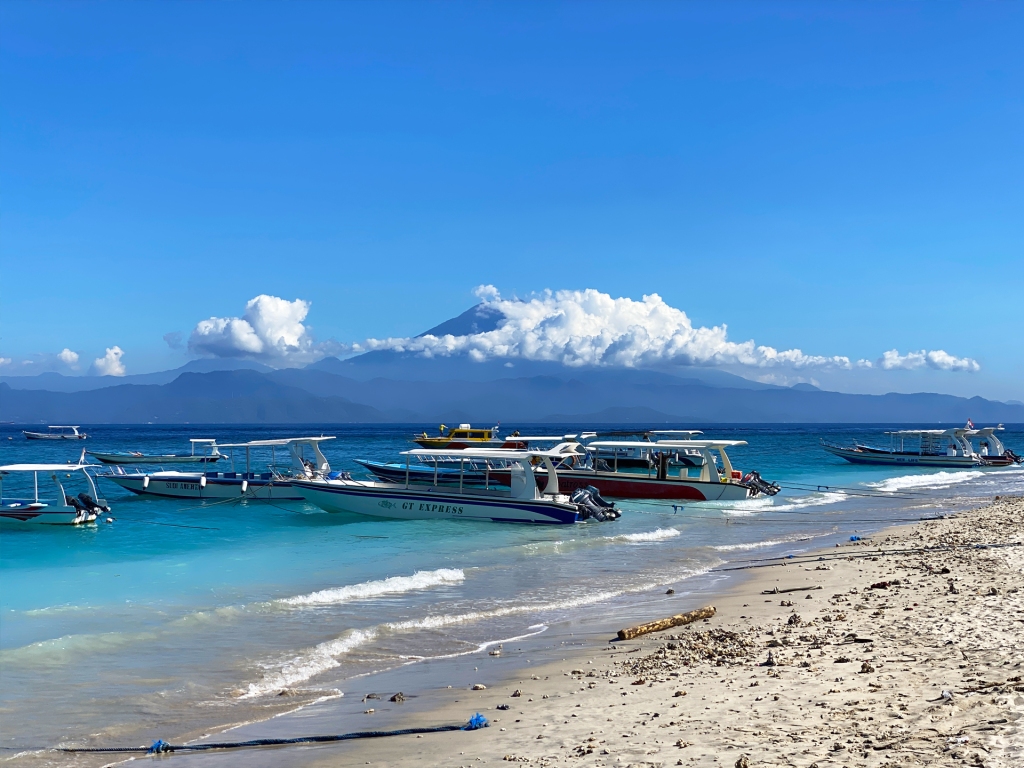 Jungutbatu Beach in Nusa Lembongan, a small island off of Bali, Indonesia. A blue water breach with a large volcano in the horizon.