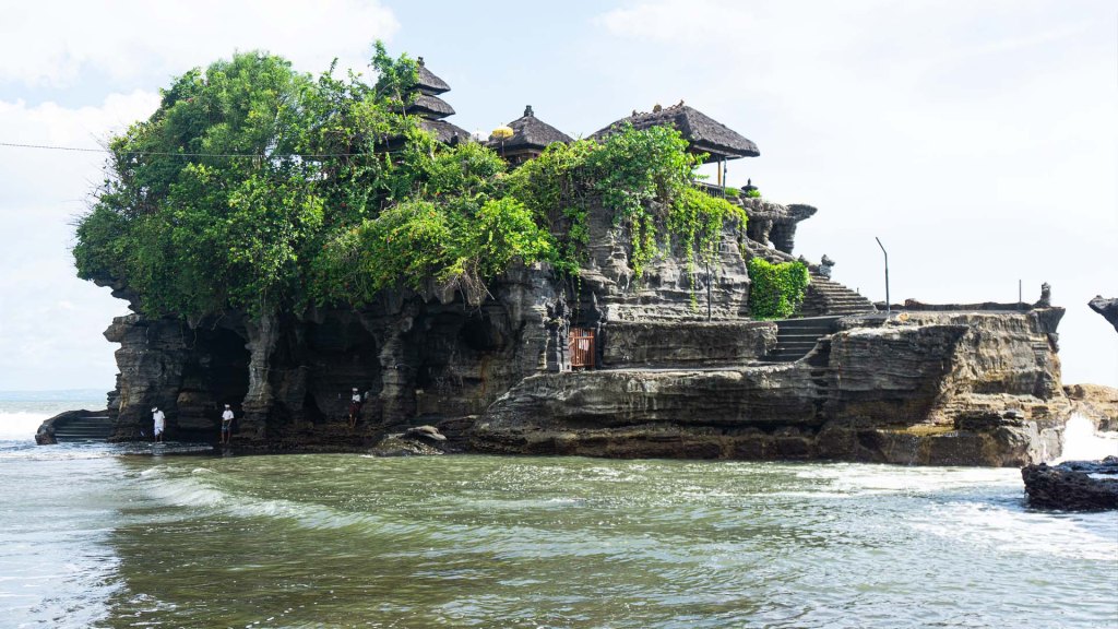 Tanah Lot Temple, an ancient Hindu temple in Canggu, Bali carved into a large off-shore sea rock.