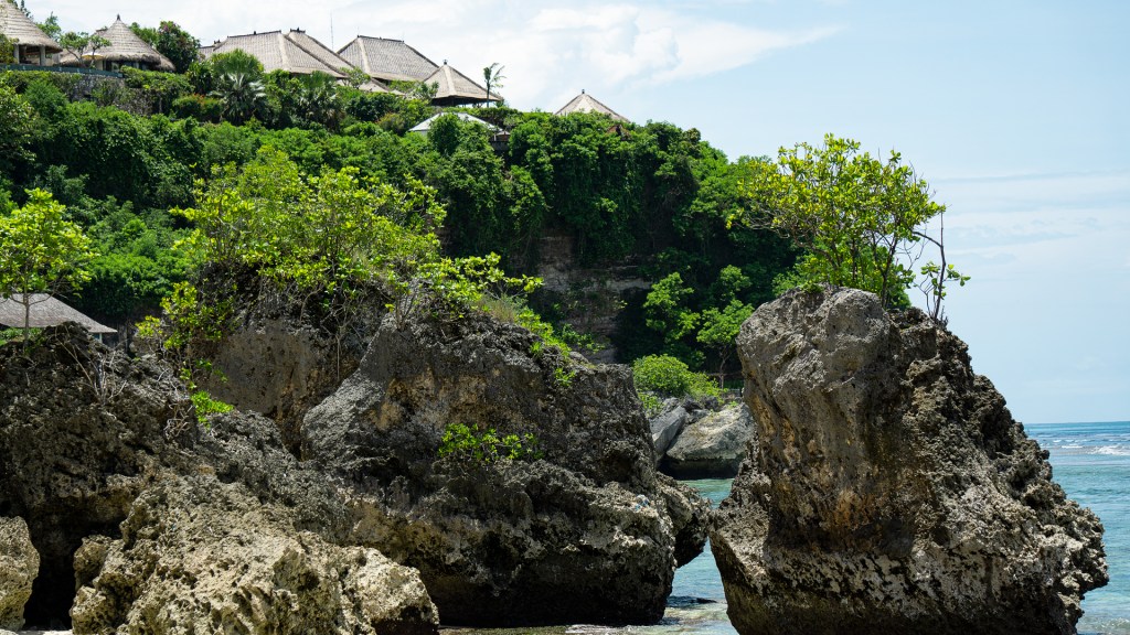 Large rocks and a cliff in front of a beach in Uluwatu, Bali.