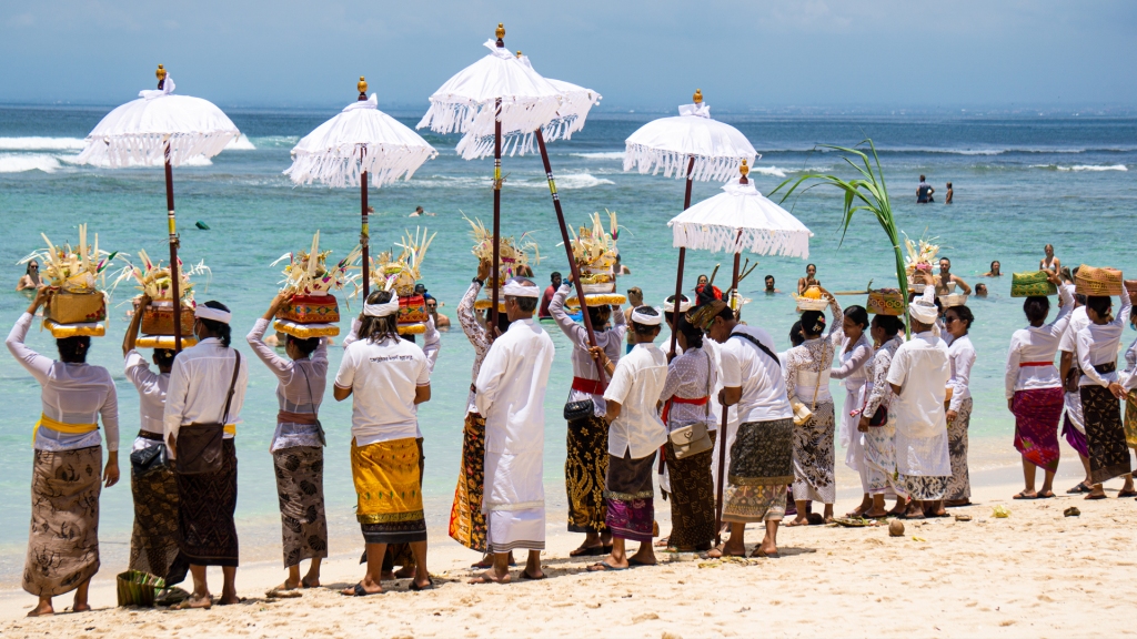 A group of local Balinese people in front of the beach performing a religious ritual at Padang P