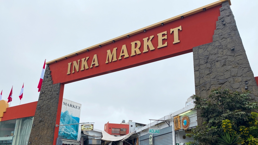 A large arch with a red background and yellow font reading, Inka Market in Lima, Peru.