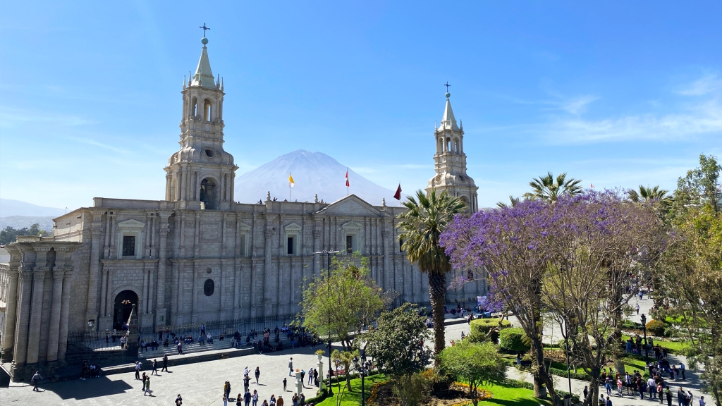 The Plaza de Armas in Arequipa, Peru, complete with a large white cathedral, and Volcano Misti between the two steeples of the cathedral.
