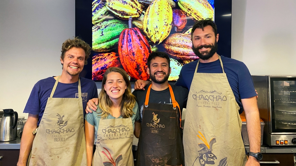 A group of 4 people wearing aprons that say Chaqchao Chocolates, in a chocolate making class in Arequipa, Peru.