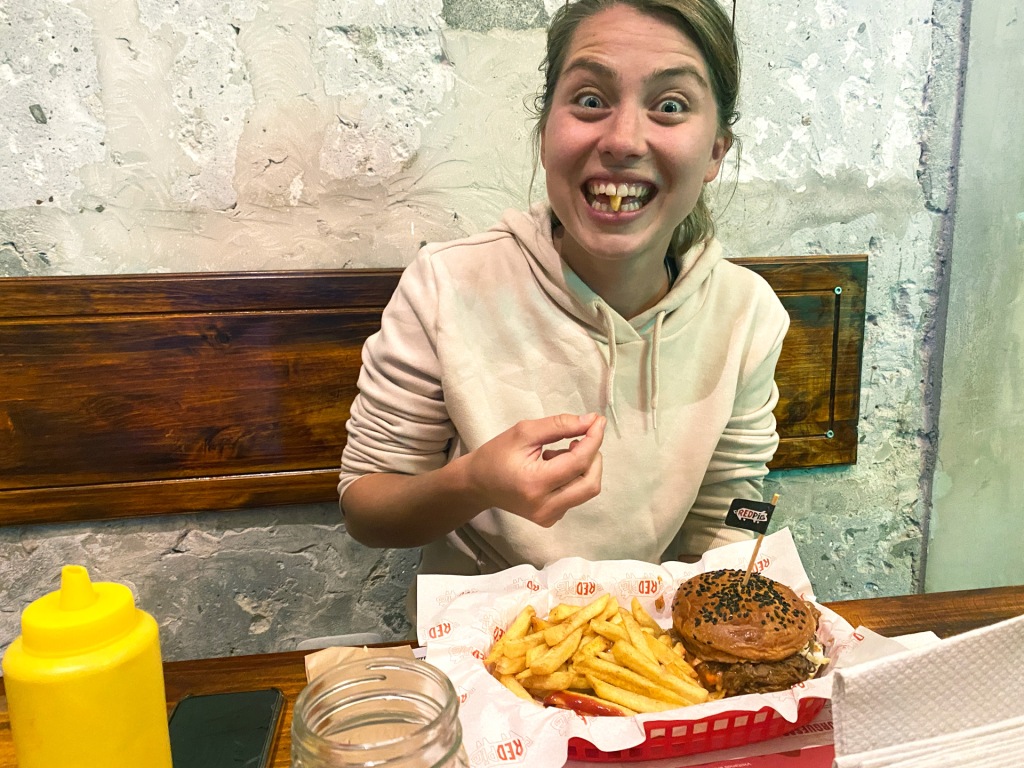 A woman eating a pulled pork sandwich and french fries at a restaurant in Arequipa, Peru.