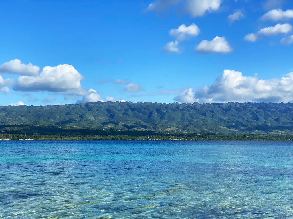 A very blue ocean with green, hilly mountains on the opposite side in Moalboal, Philippines.