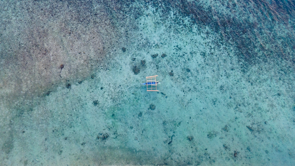 A fishing boat in the middle of very blue water in the ocean in the Philippines.