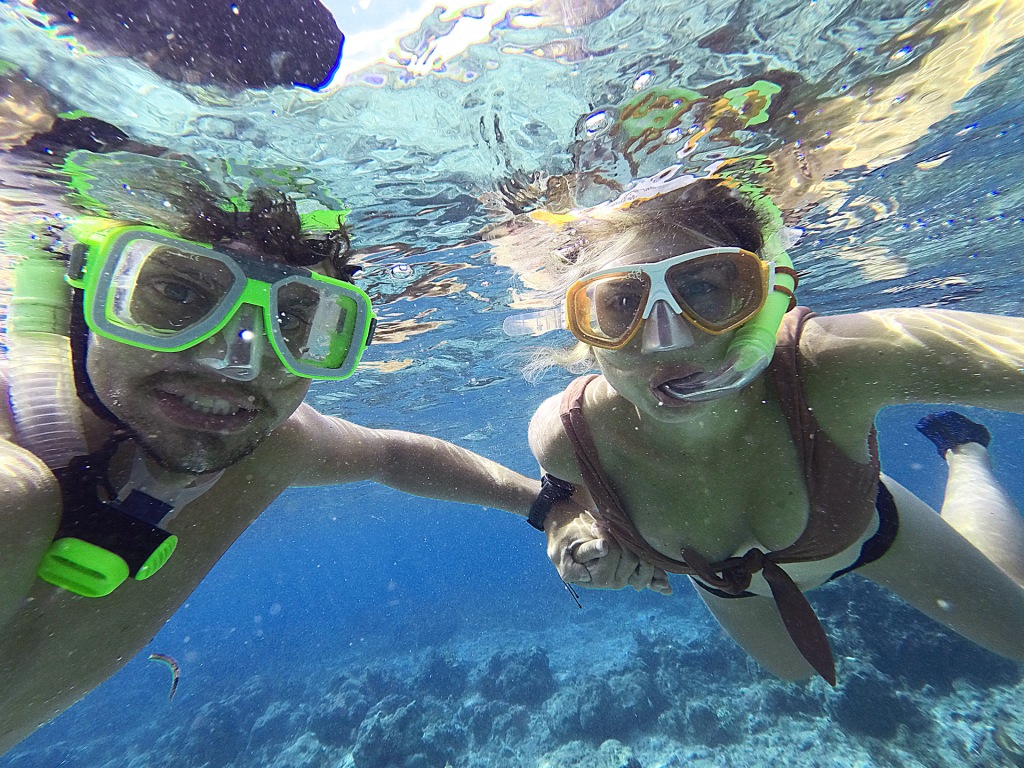 A man and a woman holding hands while snorkeling in the ocean.