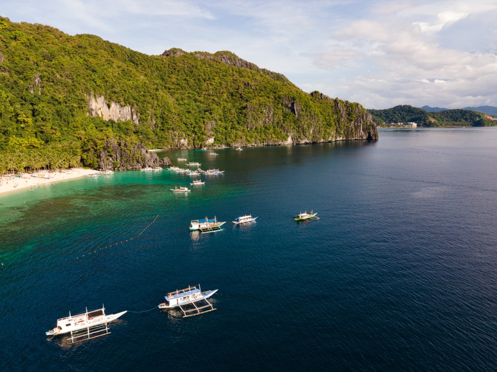 A drone photo of an island with boats around it in El Nido, Philippines.