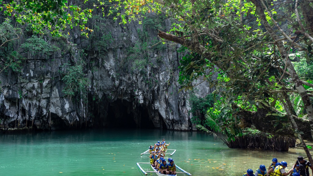 Two wooden boats entering the opening of the Puerto Princesa Subterranean River for a tour.