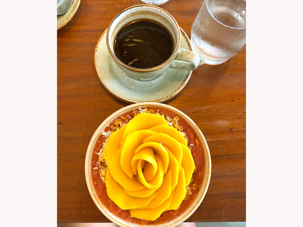 A cup of coffee and a smoothie bowl with a mango in the shape of a flower from Shaka Cafe in Panglao, Philippines.