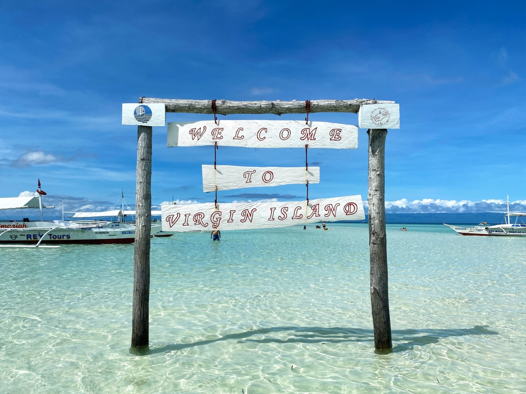 A wodden sign reading "Welcome to Virgin Island" on the Virgin Island sand bar in the Philippines.