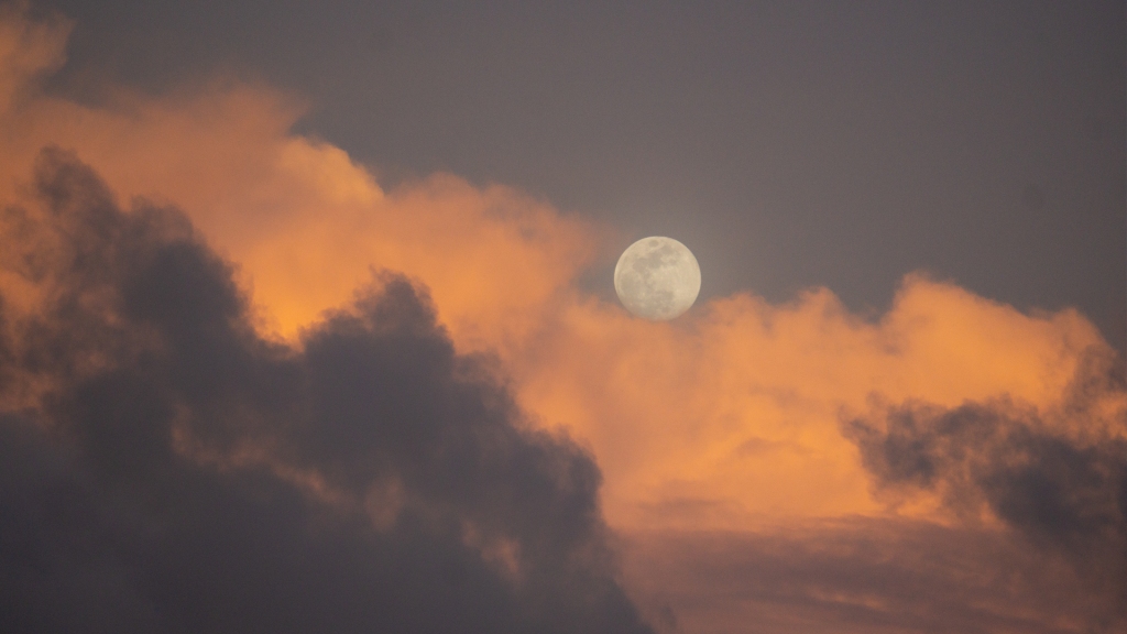 A full moon during the sunset.